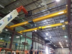 A telehandler and crane in a warehouse.