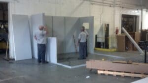 Men building a modular office in a warehouse.