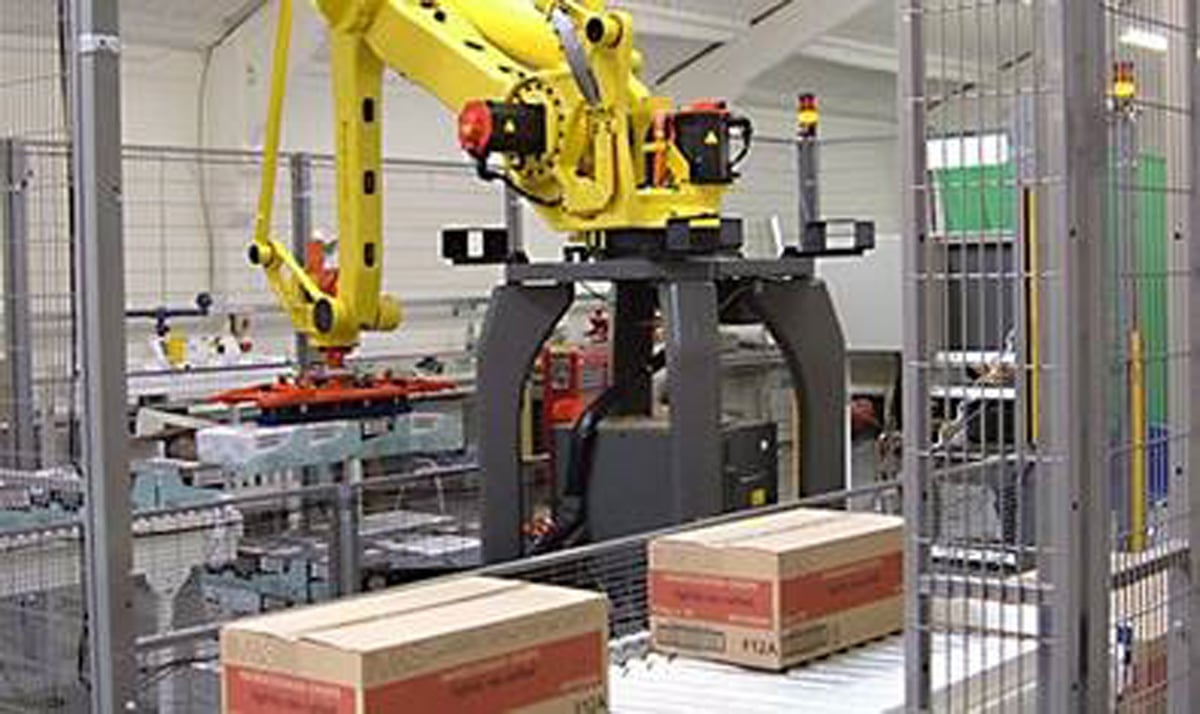 A pallet robot assembling products on a conveyor belt in a factory.