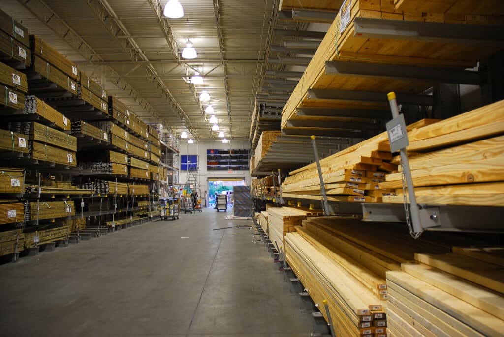 A well-organized warehouse with stacked lumber on metal shelving units, ready for distribution.