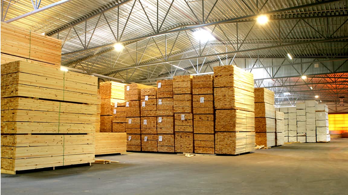 Stacks of lumber organized in a spacious warehouse.