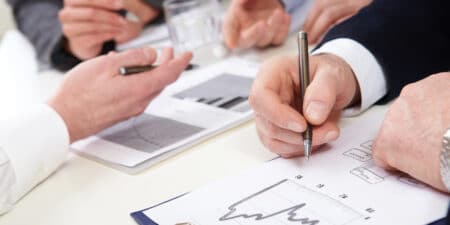 Professionals engaged in a detailed business analysis with charts and graphs during a collaborative meeting.