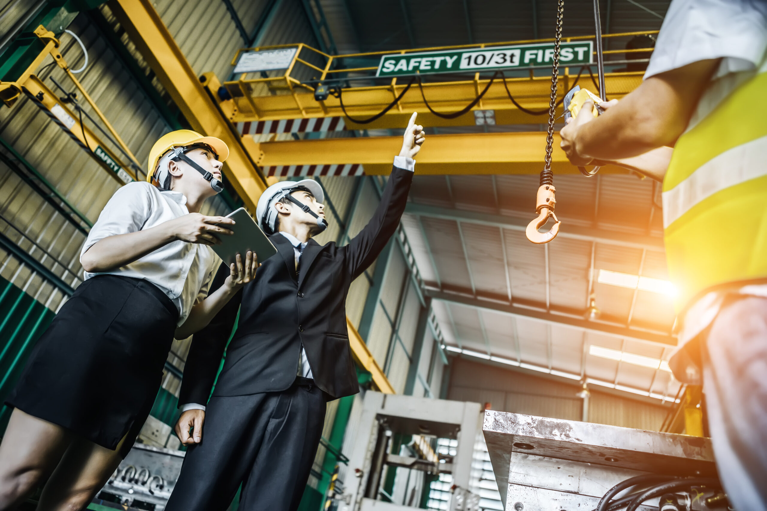 Team of three wearing PPE looking up at an overhead crane during training